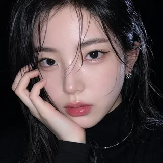 A close-up, face-filling portrait of a young Korean woman with wet black hair framing her face. She has a cool pink glass lip, subtle makeup, and is looking directly at the camera with a calm, distant expression. A silver necklace and small earrings are visible.