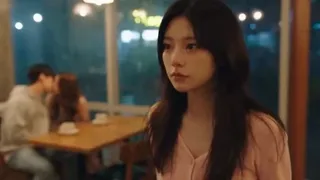 A young Korean woman in a pastel pink top crying intensely in a dimly lit café with rain outside, showing raw emotion and heartbreak.