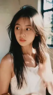 A woman's face in a close-up shot, showing a range of subtle emotions from thoughtful to a hesitant smile, with gentle wind effects.