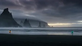 Two mages, Nerissa and Haldor, locked in a magical duel on a dark, storm-lit beach with crashing waves and lightning.