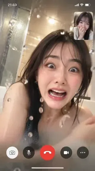 A close-up shot of a wet-haired woman looking alarmed on a smartphone video call inside a humid bathroom with water droplets on the lens.