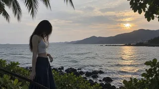 An amateur smartphone snapshot of a young woman standing by a tropical coastal walkway with the sea in the background.