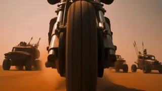 A masked rider on a custom motorcycle speeds through a dusty desert highway, pursued by armored vehicles, with explosions and dust in the background.