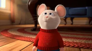 3D animation of Stuart Little, a small mouse, looking up at Snowbell, a smug white cat sitting on a couch, during their first encounter in the living room.