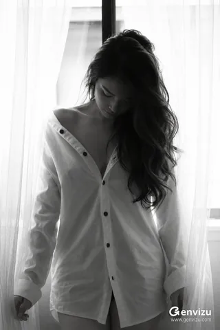 A moody portrait of a person in a white shirt standing near a window with sheer curtains filtering soft light.