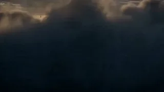 A giant, translucent whale glowing gold and blue swims through storm clouds above mountain peaks, with airships following and the word 'MORNING' in the sky.