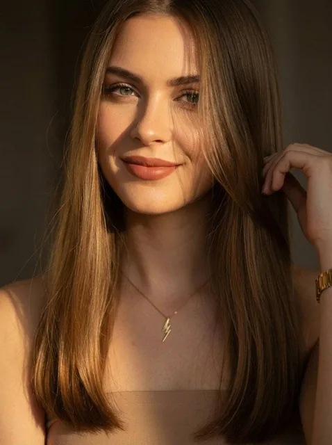 A cinematic close-up portrait of a young woman with long straight light brown hair, soft green eyes, and natural makeup,