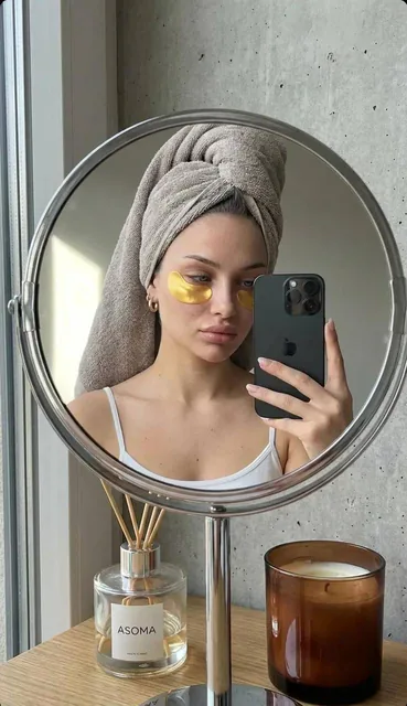 A highly realistic mirror selfie of a young woman taken through the reflection of a round tabletop mirror with a chrome