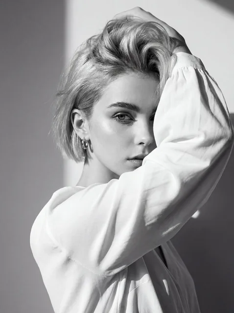 Use the attached image of the model as facial reference and physical features. Black and white high-fashion editorial po