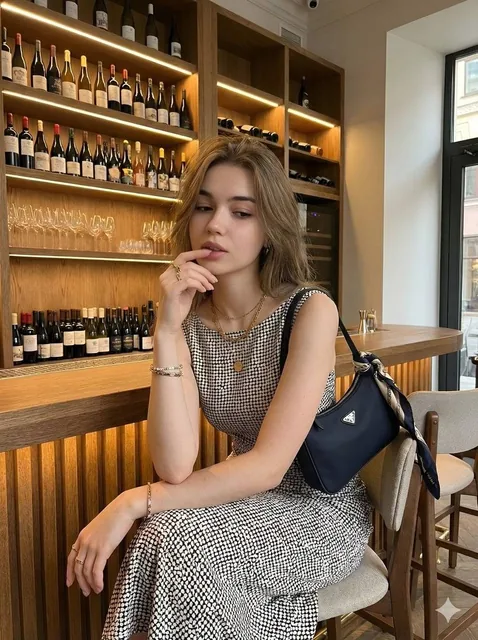 Young beautiful woman with long wavy hair, elegant sleeveless polka dot midi dress black and white pattern, sitting thou