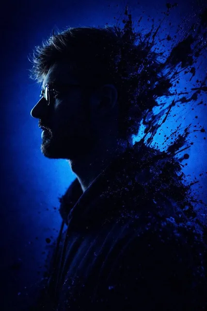 A dramatic, stylized portrait of a silhouetted figure in profile against a deep electric blue background, with intense black and sapphire paint splashes bursting outwards.