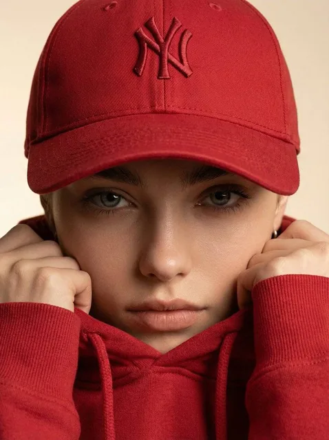 Ultra-realistic fashion beauty crop of a female model wearing the reference red baseball cap and matching red hoodie. Fr