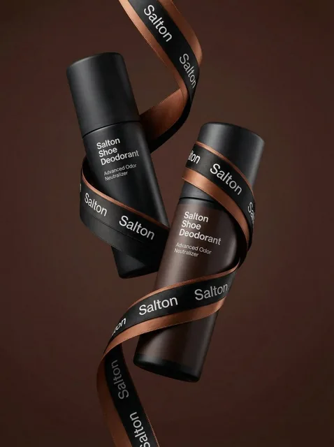 A product photo in a premium advertising style. Two tall matte bottles of Salton Shoe Deodorant levitate in the air in a