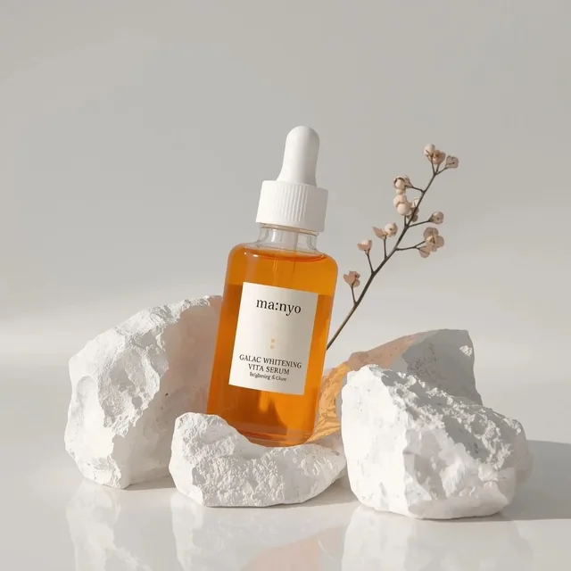 Minimalist studio product photography of an amber glass dropper serum bottle with white cap, labeled “ma:nyo Galac White