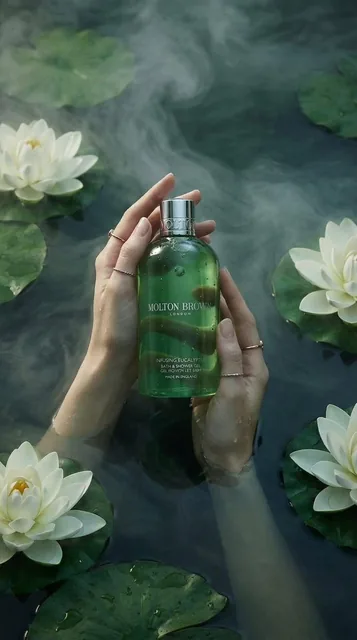 Luxury product photography of a green translucent bath and shower gel bottle held gently by two feminine hands submerged