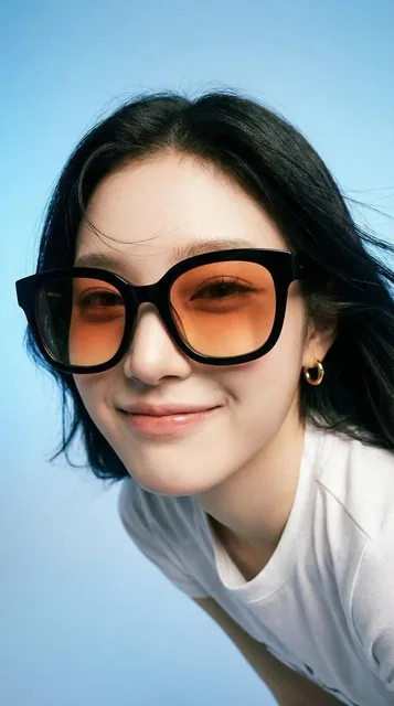Photorealistic editorial portrait of a smiling woman using the exact same face from the reference image. She wears overs