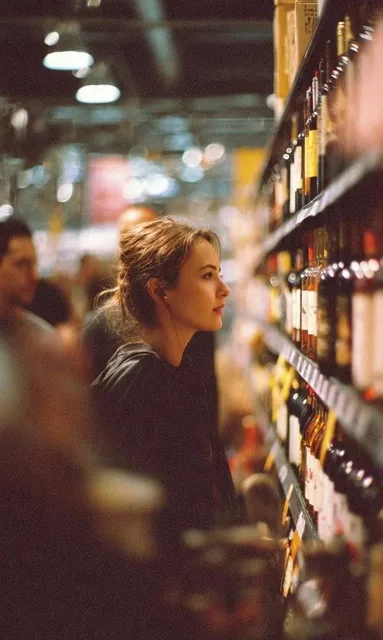 A cinematic side-profile portrait of a young woman standing in a grocery store aisle, carefully looking at a shelf fille
