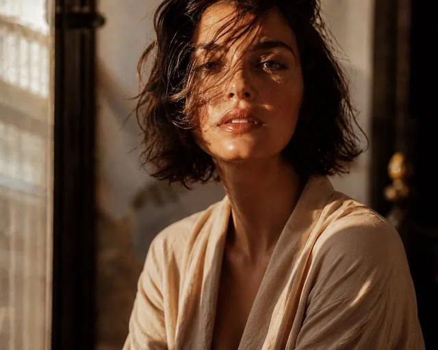 Cinematic editorial close-up of an elegant young woman with a tousled chin-length brunette bob, a few soft waves falling