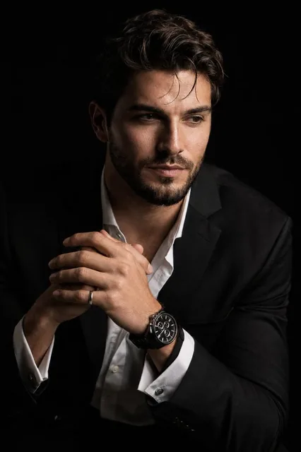 Create a hyper-realistic 8K cinematic portrait of the [Uploaded Person] in a dramatic chiaroscuro style. The subject is