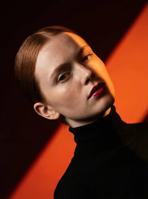 Ultra-high-fashion editorial beauty portrait of a fair-skinned female model with sleek center-parted hair tightly pulled