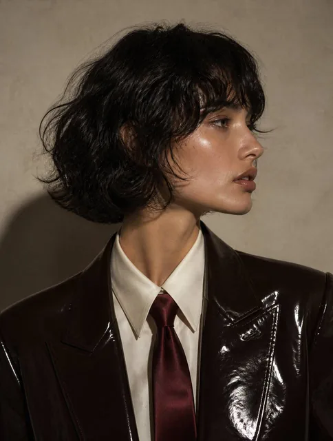 A high-fashion editorial medium close-up photograph of a woman with a sharp side-profile view, captured in a moody and s