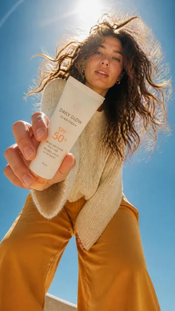 Ultra-wide-angle low-angle 9:16 cinematic fashion editorial shot from ground perspective, a young woman leaning over the