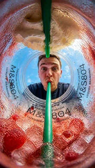 { "prompt": "POV from inside an M&S804 strawberry frappuccino cup looking upward, extreme fisheye lens distortion, cinem