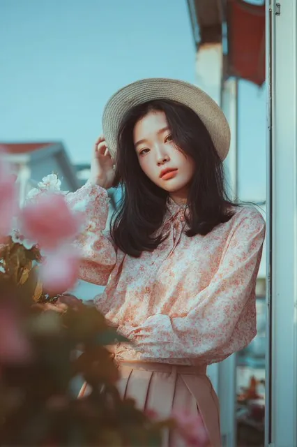 A portrait of a woman in a serene room, wearing a silken blue top and denim, with raven hair and hazel eyes, bathed in soft K-beauty lighting with bokeh background and pastel color grading.