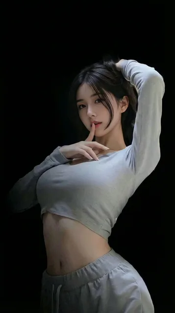 A refined young Asian woman with long black hair poses against a pure black background. She wears a light grey cropped long-sleeve top and matching athletic pants. In a side profile, she gently holds the back of her head with one hand and places a finger to her lips with the other, exuding a confide