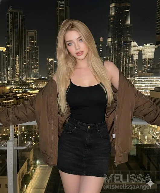 A photorealistic cinematic portrait of a beautiful blonde model with blue eyes, wearing a black sheer top and bomber jacket, standing on a high-rise balcony overlooking the illuminated Dubai skyline at night, with the Burj Khalifa visible, featuring dramatic lighting and sharp detail.