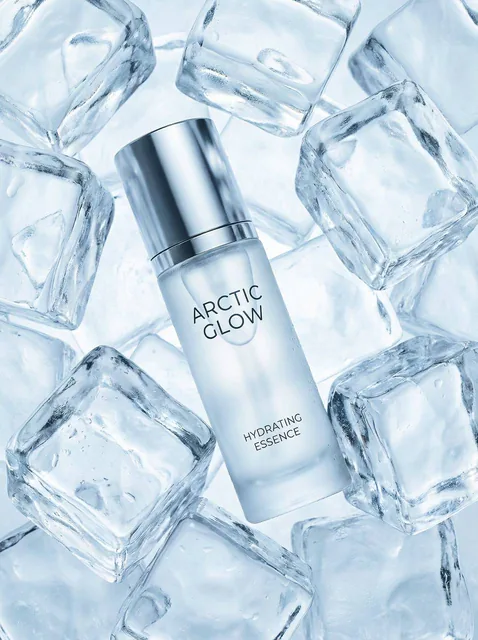 Hyper-realistic luxury skincare product at the center, completely surrounded by dense, clear ice blocks, with sharp highlights and condensation droplets against a pale blue backgro