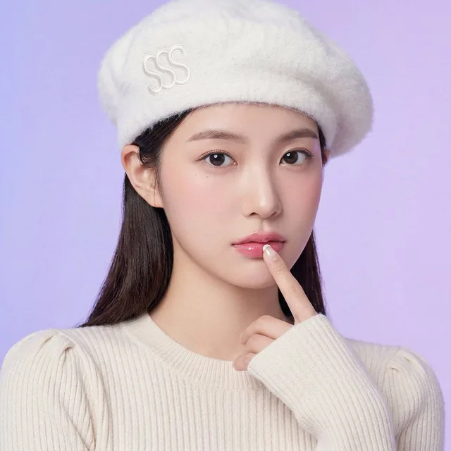 A close-up studio portrait of a young woman with dark hair wearing a fluffy white beret and a cream knit sweater, posing against a seamless pastel purple gradient background. She makes direct eye contact while gently resting her index finger on her lower lip.