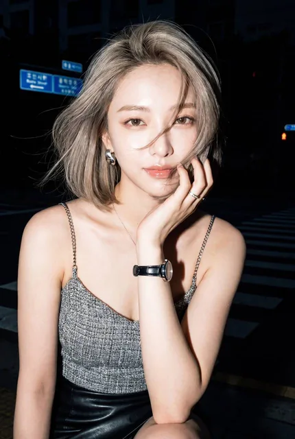 A young woman with a short voluminous dark bob haircut stands on a late-night city crosswalk, wearing a grey tweed camisole and black leather skirt, with one hand near her face, making confident eye contact under strong on-camera flash, in a Y2K CCD snapshot style.