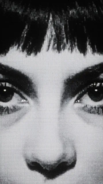 tight close-up portrait of a face focusing on eyes and nose, dark hair with jagged bangs, inten...