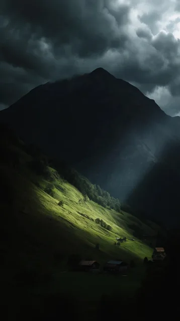 massive dark mountain under heavy storm clouds, dramatic shaft of sunlight striking a steep gre...
