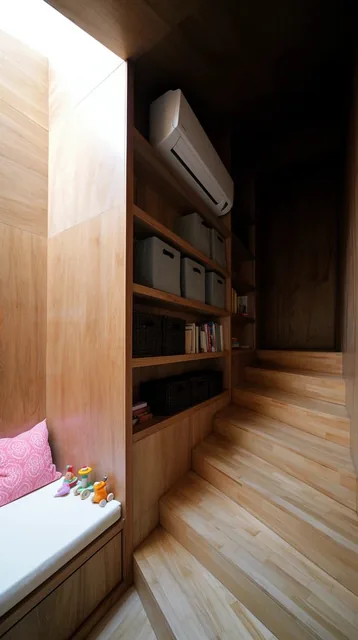 A compact minimalist interior dominated by varying tones of natural wood paneling. A light-wood...