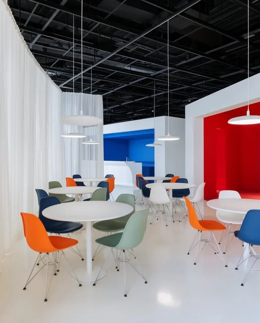 A bright, open-plan architectural space featuring a glossy white floor and an exposed industria...