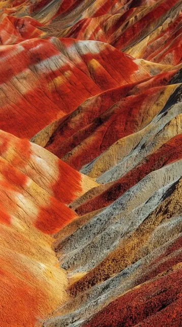 vibrant rolling badlands, striking geological strata, diagonal ridges of deep red, rusty orange...