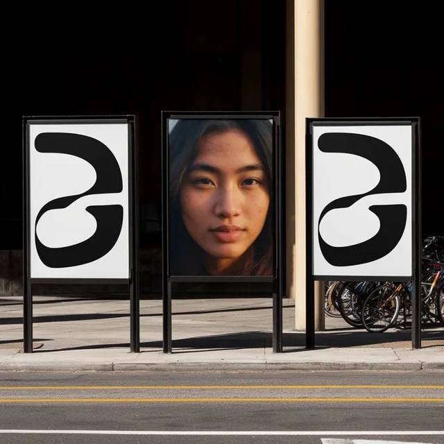 Three freestanding advertising displays stand side-by-side on a sunlit concrete sidewalk border...