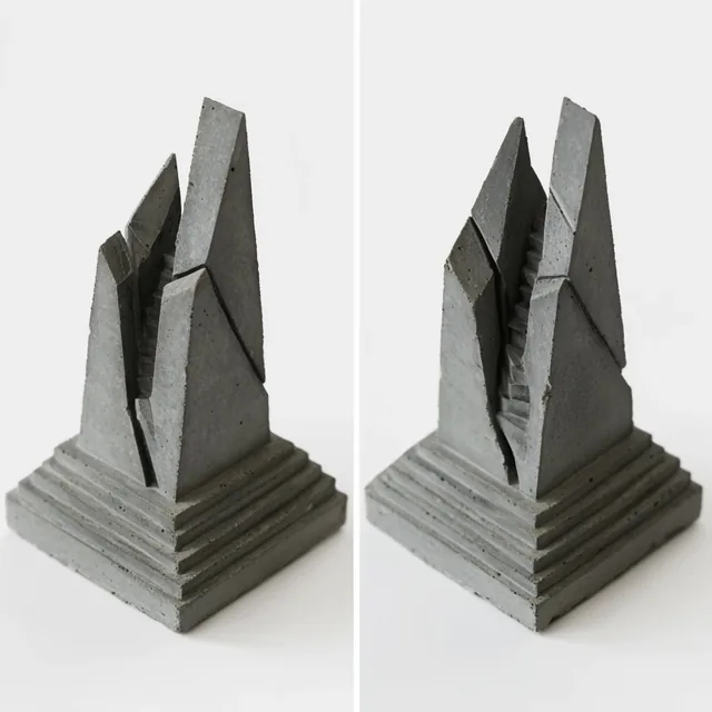 Two angled views of a miniature brutalist concrete sculpture on a stark white background. The m...