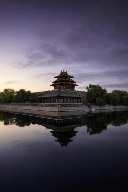 A multi-tiered East Asian watchtower with curved roofs stands on a stone wall corner, perfectly...