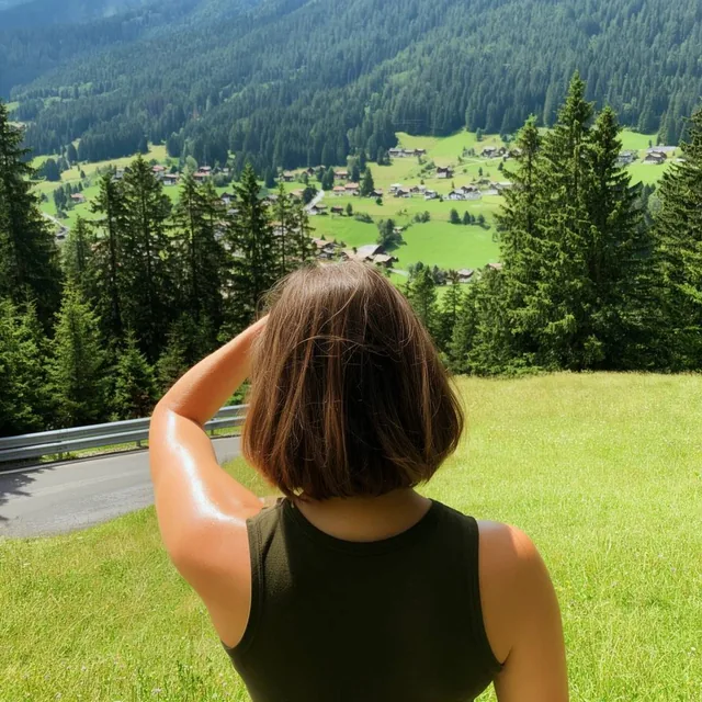 woman viewed from behind with short brown hair, dark olive green sleeveless top, left arm raise...