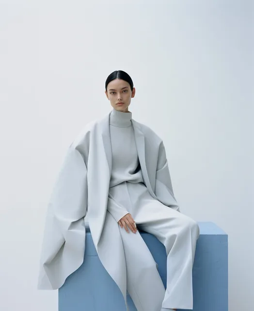 a woman sitting on top of a white cube, official jil sander editorial, blue and grey tone...
