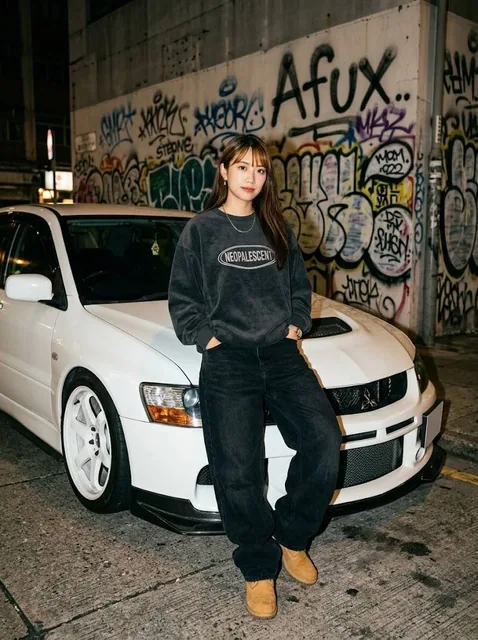 Realistic, candid full body photo of a young woman with a confident expression, leaning against a white Mitsubishi Lancer Evo IX at night, wearing 90s streetwear and tan boots, wit