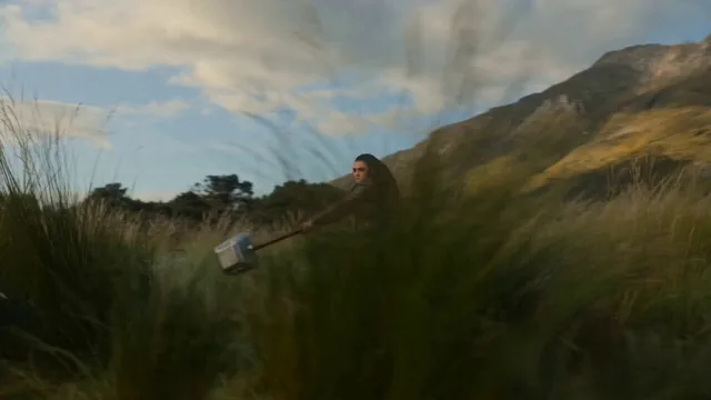 SUBJECTS: A warrior with a rune-carved stone warhammer, facing a colossal blue-green beast across a valley.