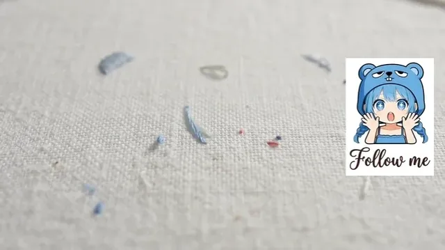A stop-motion style embroidery animation of a 2D anime character being crafted with real needle and thread.