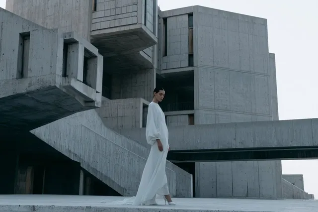 A Brutalist architectural scene with monolithic concrete slabs, repeating windows, and stark angular shadows, rendered in a cold, minimal color palette.
