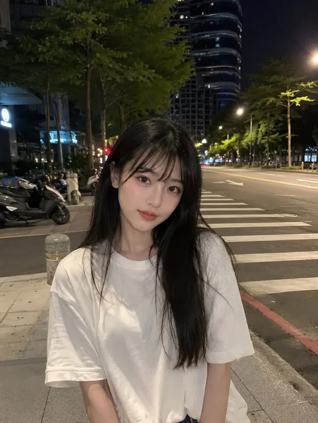 Ultra-realistic smartphone photo of a beautiful young Japanese woman with expressive brown eyes and long black hair, wearing a white t-shirt, standing on a city street at night, looking calmly at the camera.