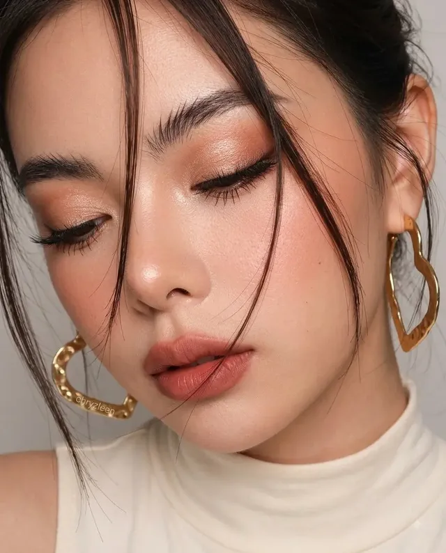 Extreme close-up portrait of an Arabian woman with closed eyes, showcasing detailed eye makeup, soft lips, and wispy hair strands across her face.