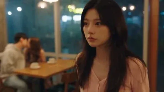 A young Korean woman in a pastel pink top crying intensely in a dimly lit café with rain outside, showing raw emotion and heartbreak.